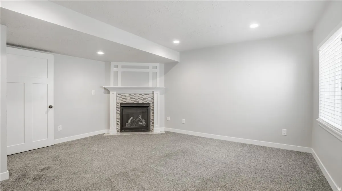 Unfurnished living room with recessed lighting, light carpet, a tile fireplace, and a textured ceiling