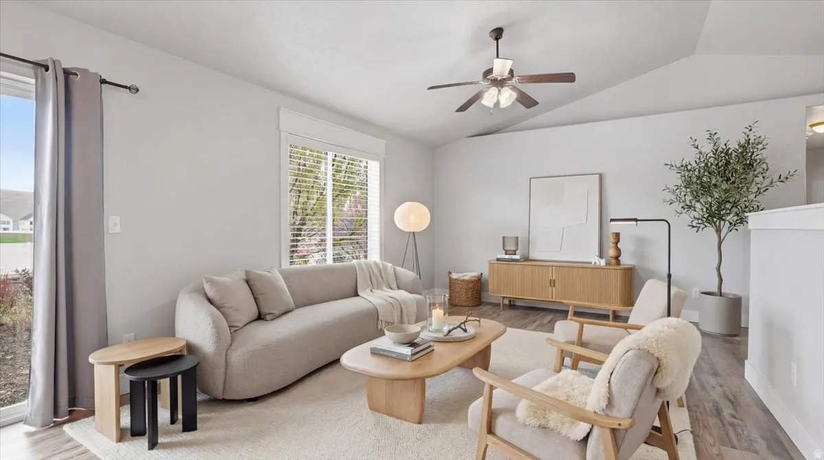 Living room with light wood-style flooring, lofted ceiling, and a ceiling fan