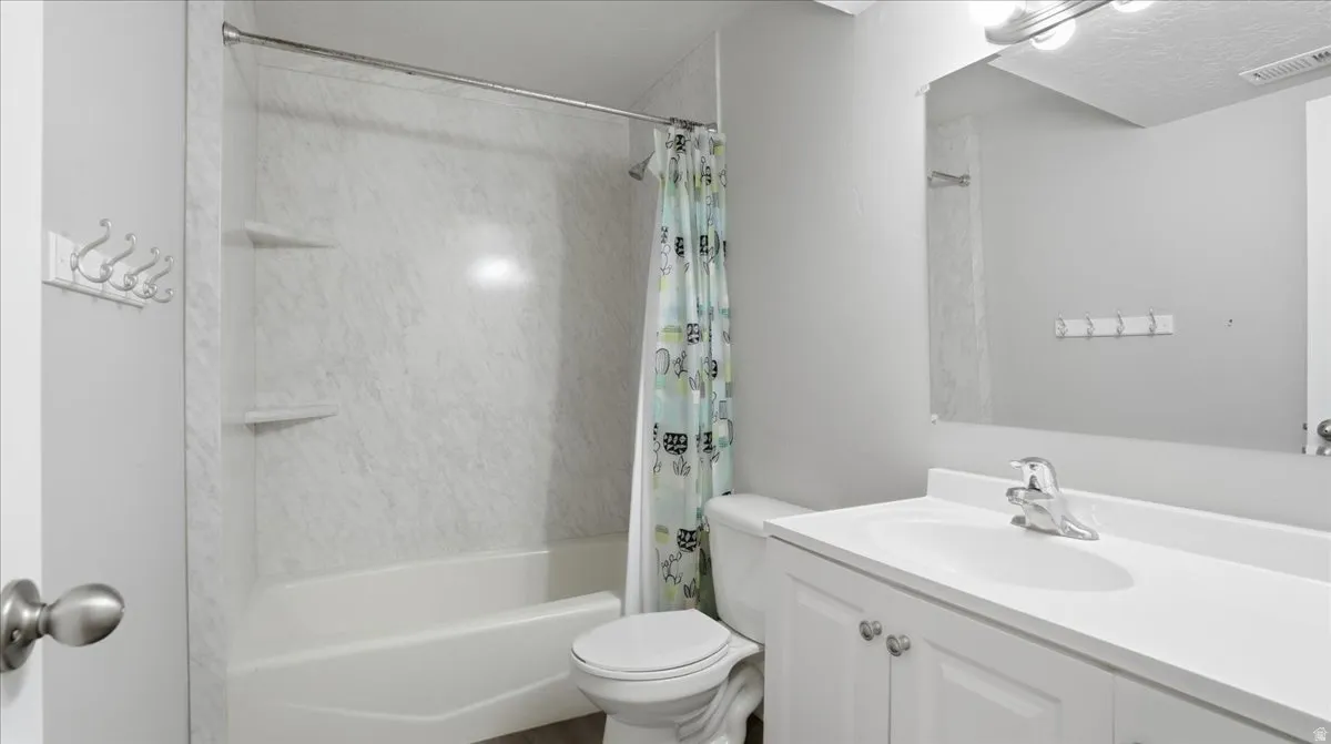 Bathroom with vanity, shower / bath combination with curtain, and a textured ceiling