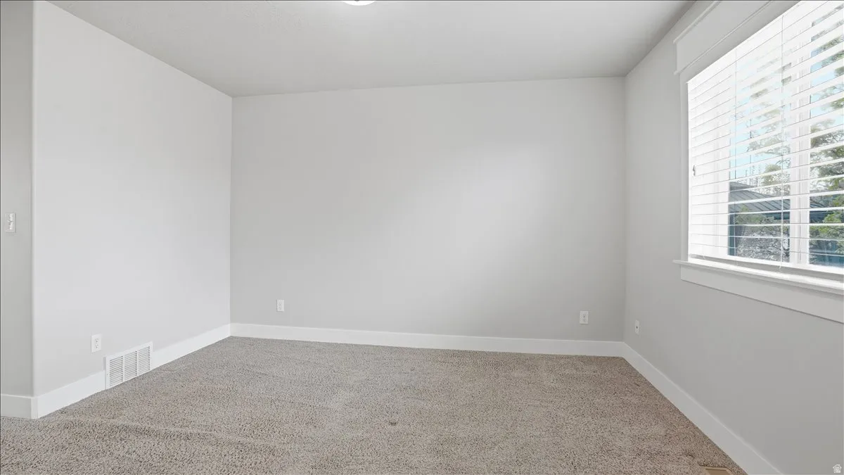 Empty room featuring light colored carpet and baseboards