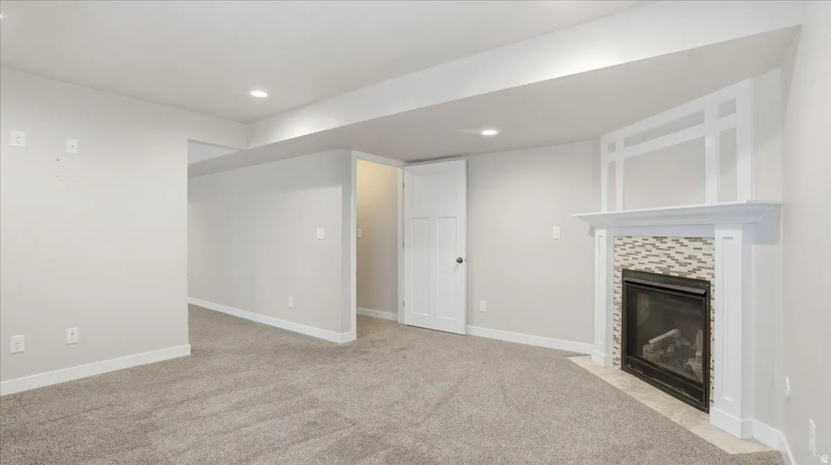 Unfurnished living room featuring light colored carpet, a tile fireplace, and recessed lighting