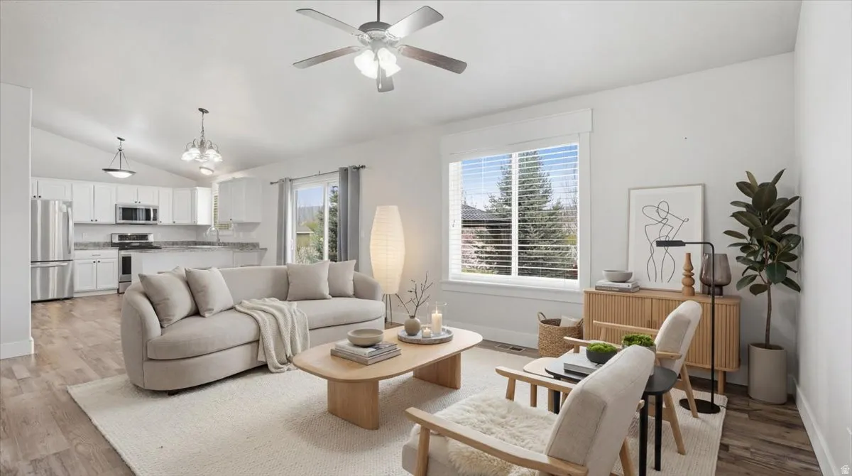 Living room featuring light wood finished floors, lofted ceiling, a chandelier, a ceiling fan, and radiator heating unit