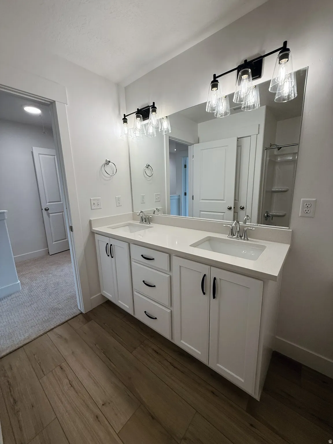 Bathroom with double vanity and dark wood-style flooringPhotos are for reference only.  Actual finishes may vary.