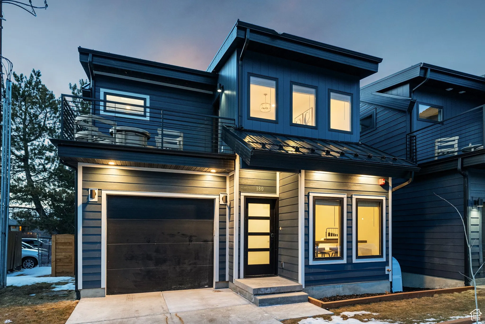 Contemporary house with a standing seam roof, an attached garage, and driveway