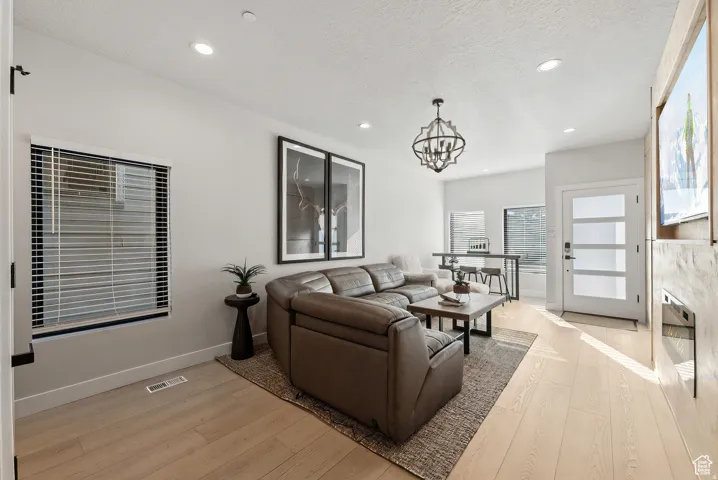 Living room featuring light wood-style floors, a chandelier, and a textured ceiling