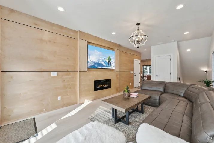 Living area with a glass covered fireplace, hanging lights, and wood finished floors