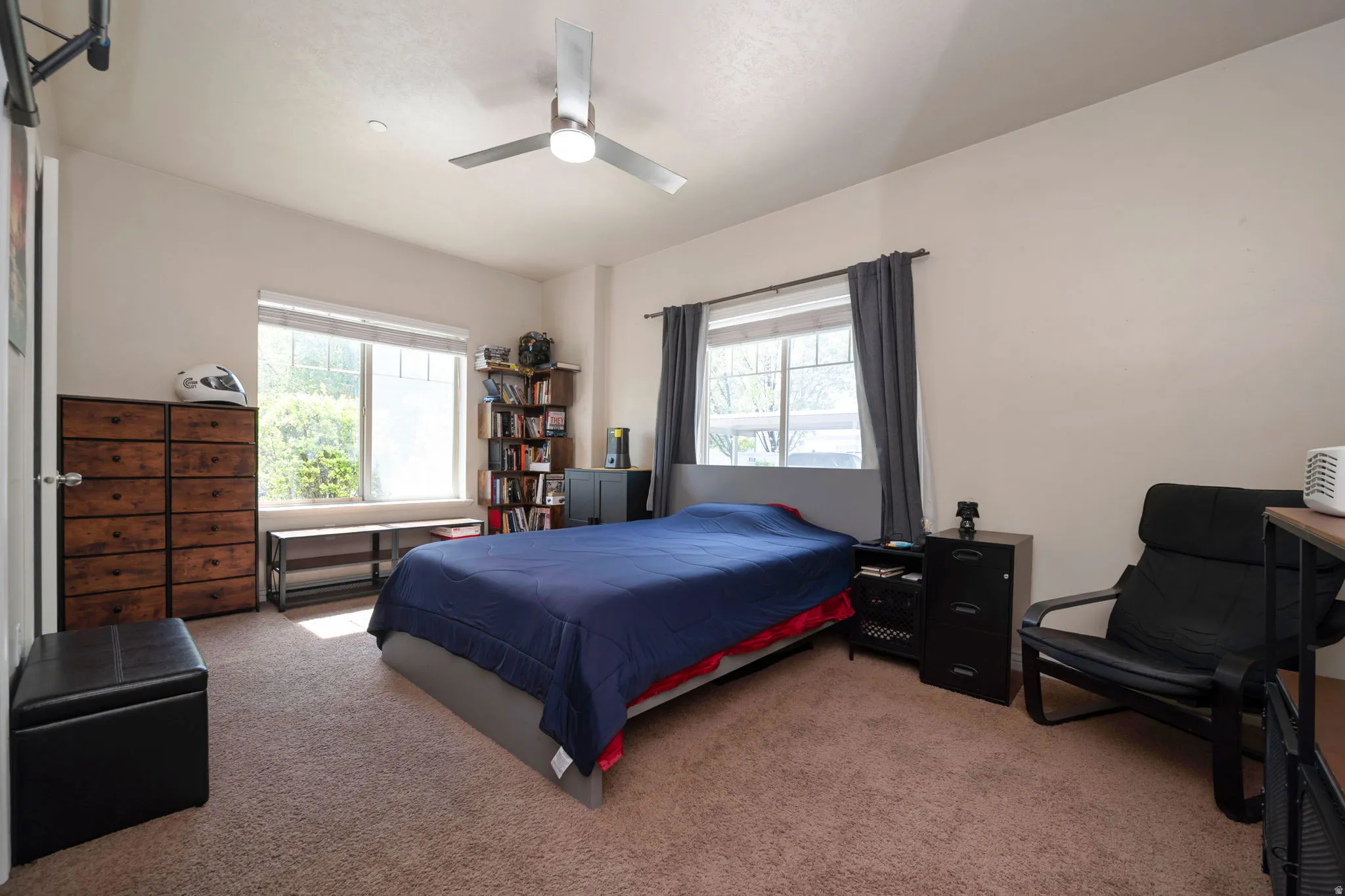 Carpeted bedroom with ceiling fan and multiple windows