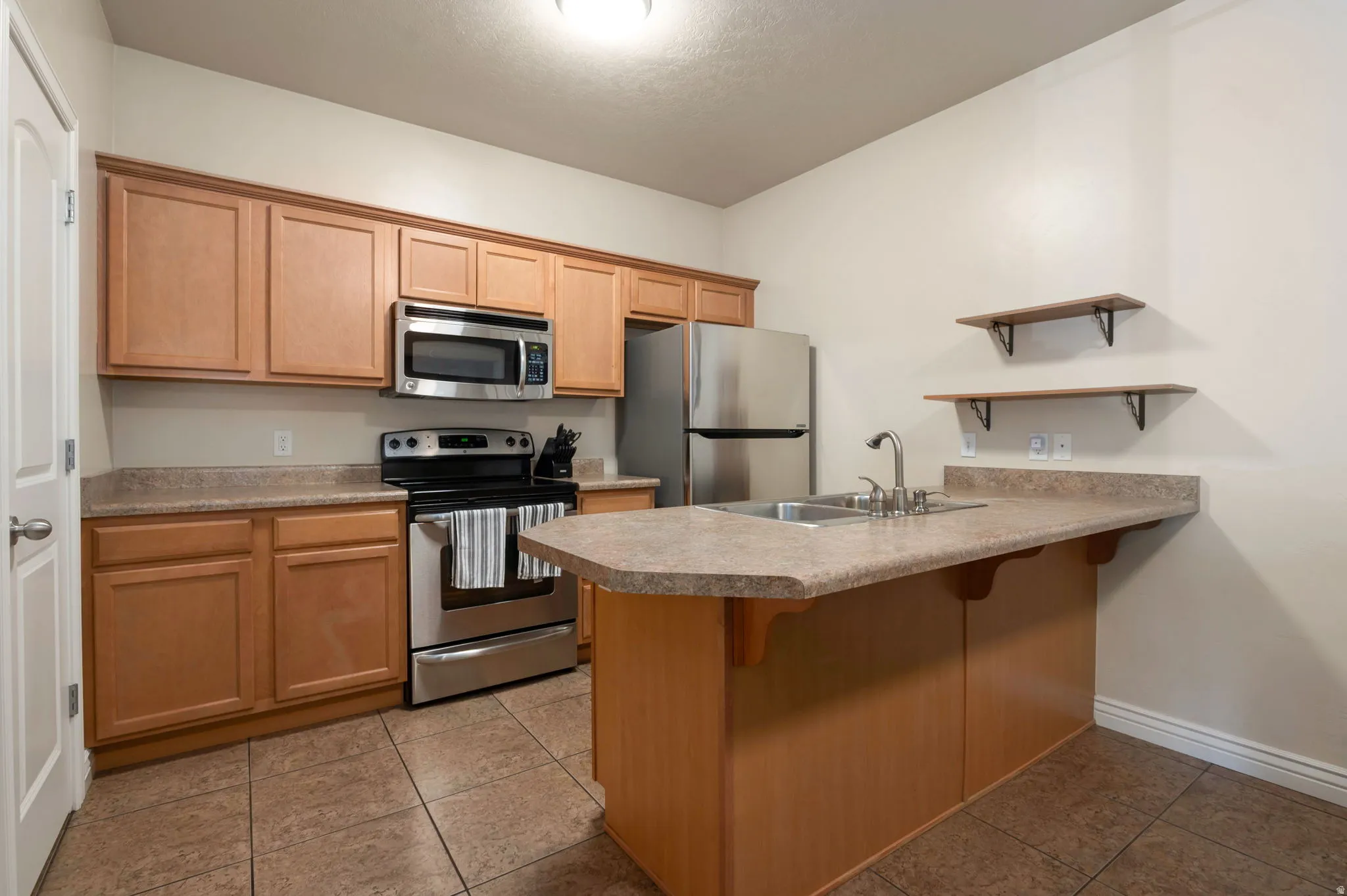 Kitchen with a breakfast bar, a peninsula, stainless steel appliances, and dark tile patterned floors