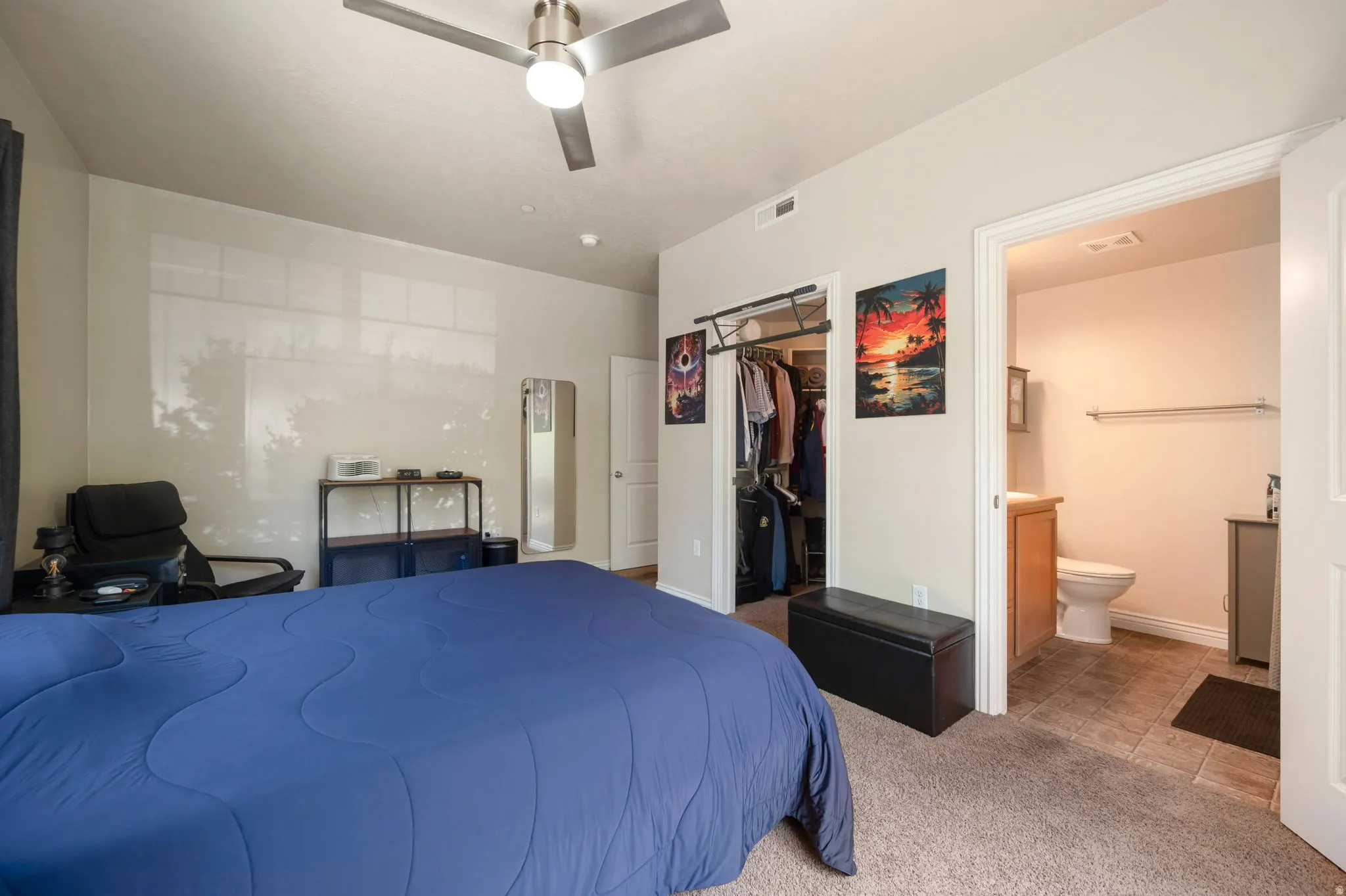 Bedroom featuring light colored carpet, a walk in closet, ceiling fan, and ensuite bathroom