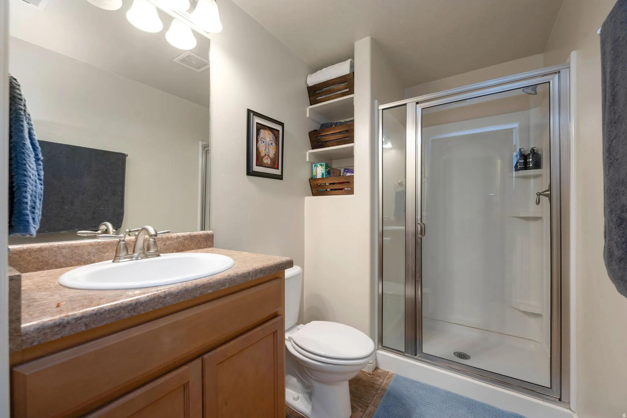 Bathroom with vanity, a shower stall, and dark tile patterned flooring