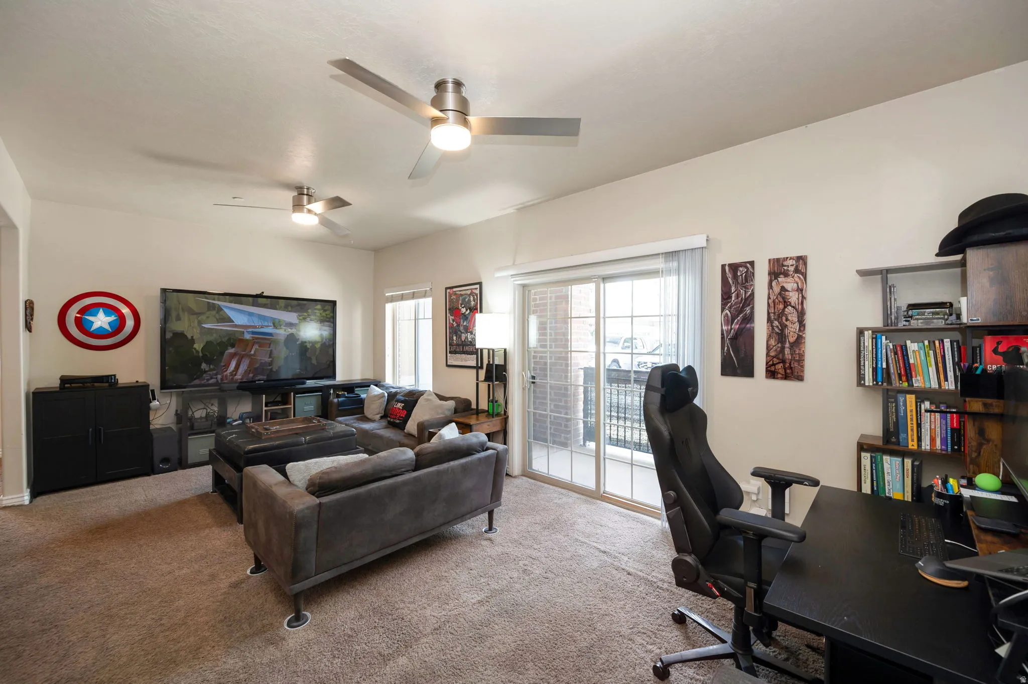 Carpeted home office featuring a ceiling fan