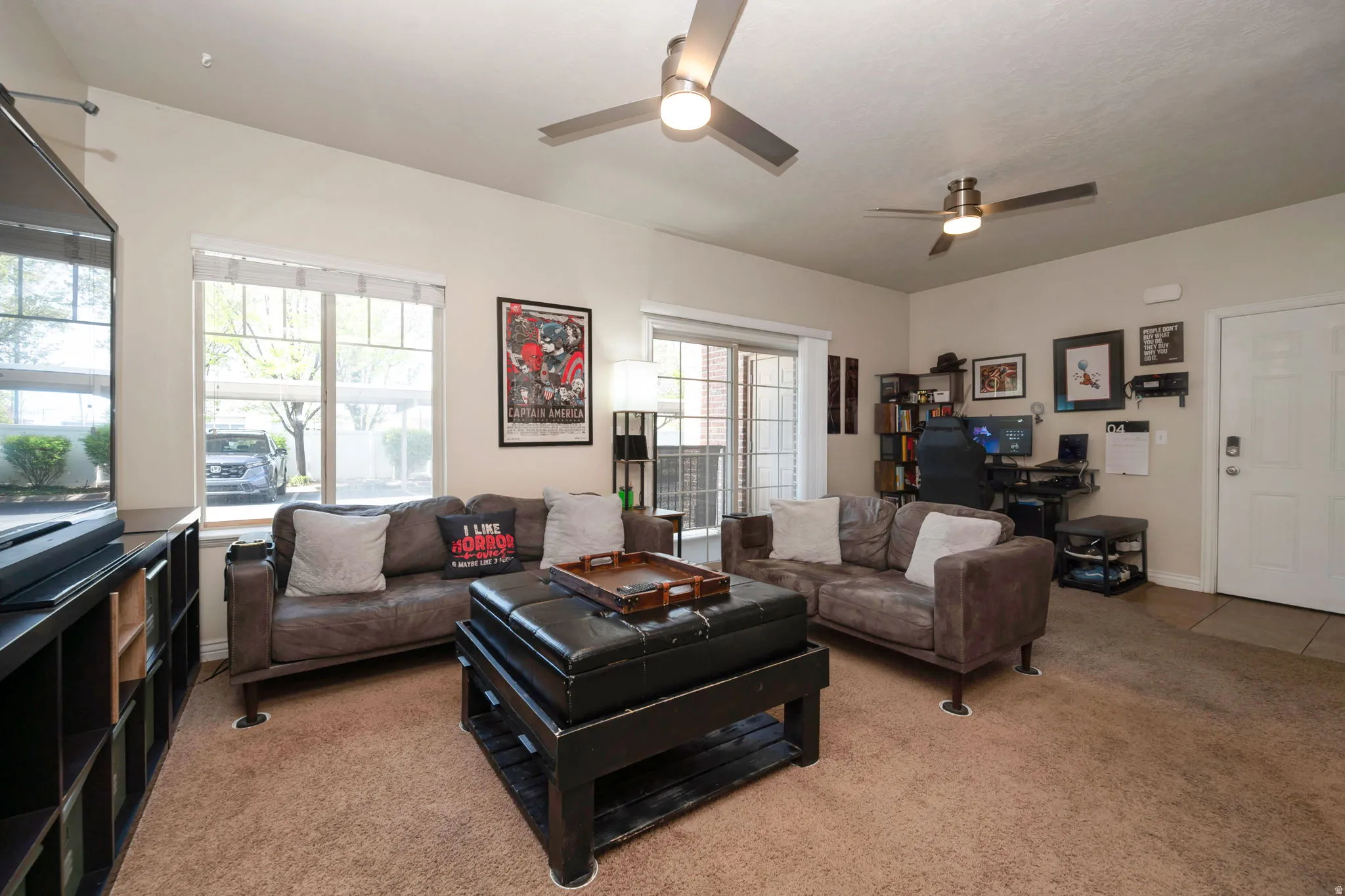 Living room featuring carpet floors, a ceiling fan, and a desk