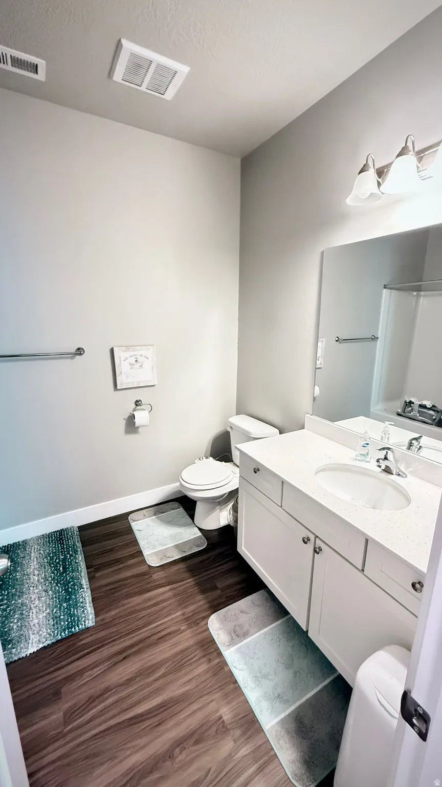 Full bathroom with vanity, dark wood-style flooring, a textured ceiling, and a shower