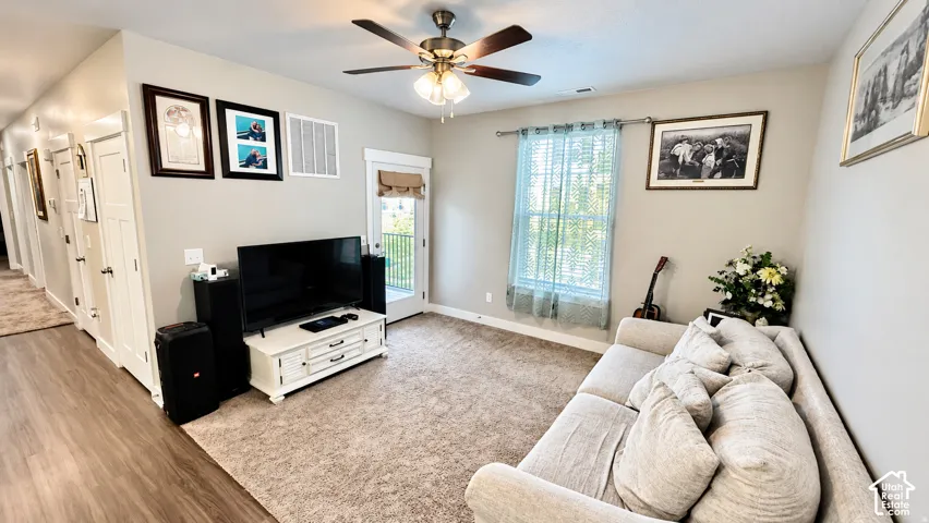 Carpeted room with a ceiling fan, a window with blinds, and a door with external access
