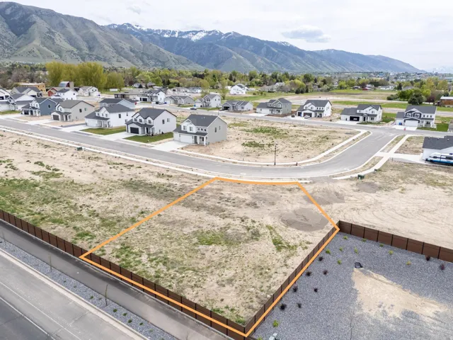Aerial perspective of suburban area with a mountain backdrop and property parcel outlined