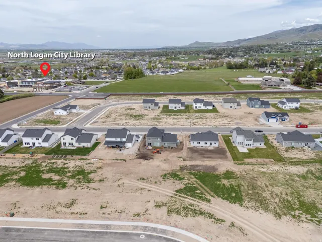 Aerial view of property and surrounding area featuring nearby suburban area and a mountainous background