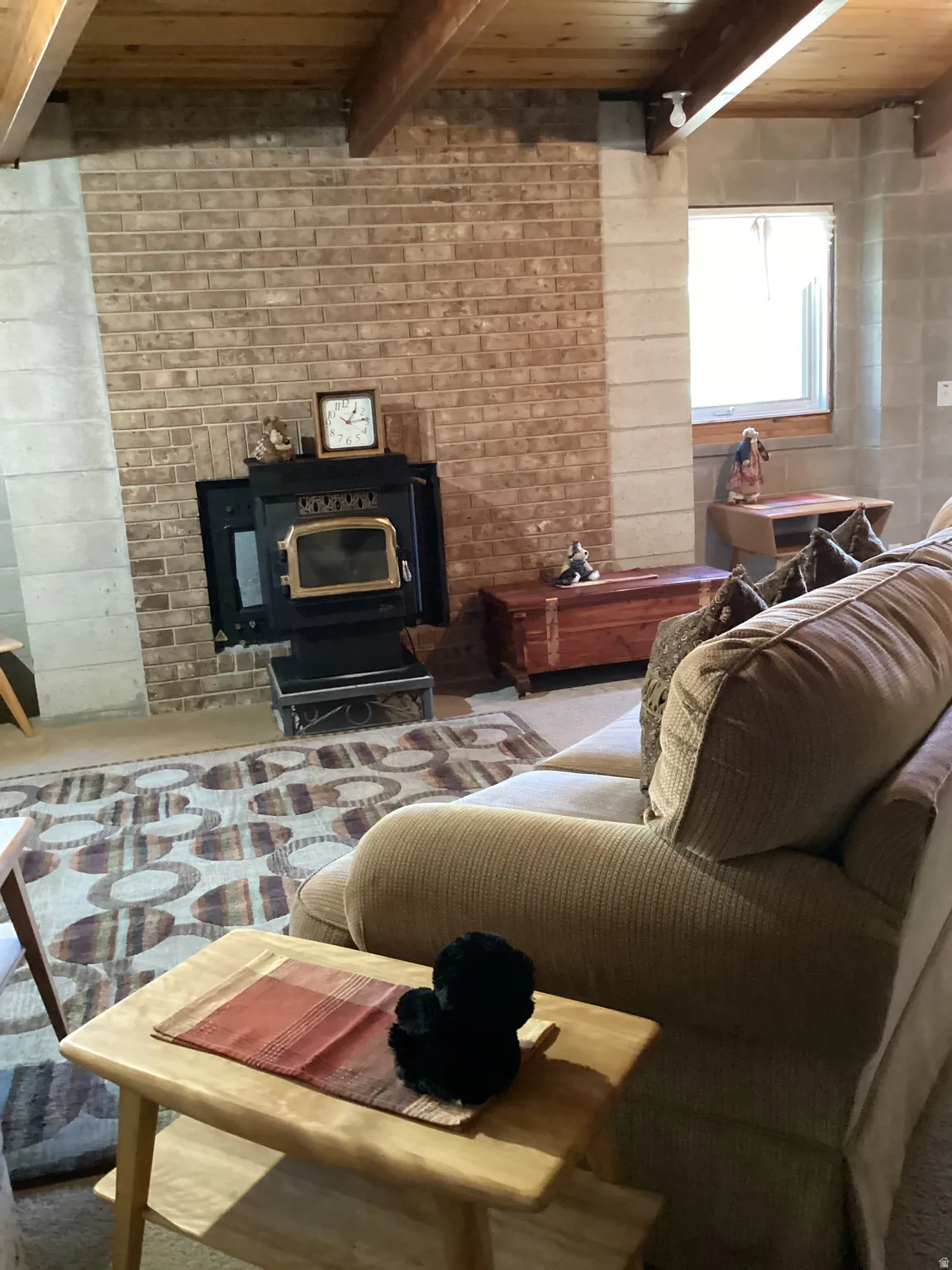 Living room with a wooden ceiling with exposed beams and a wood stove