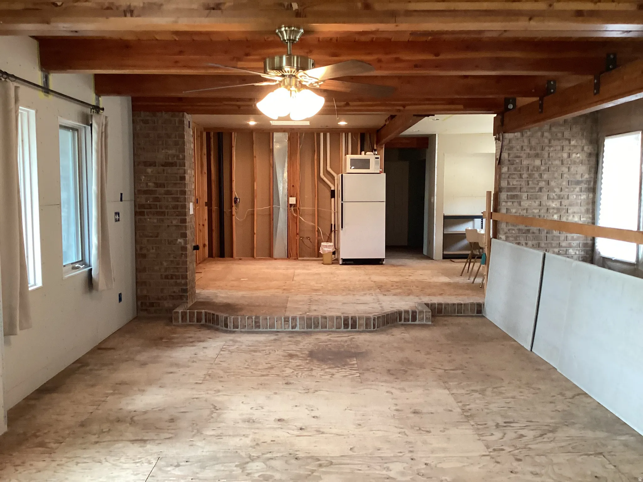 Unfurnished room with ceiling fan and brick wall