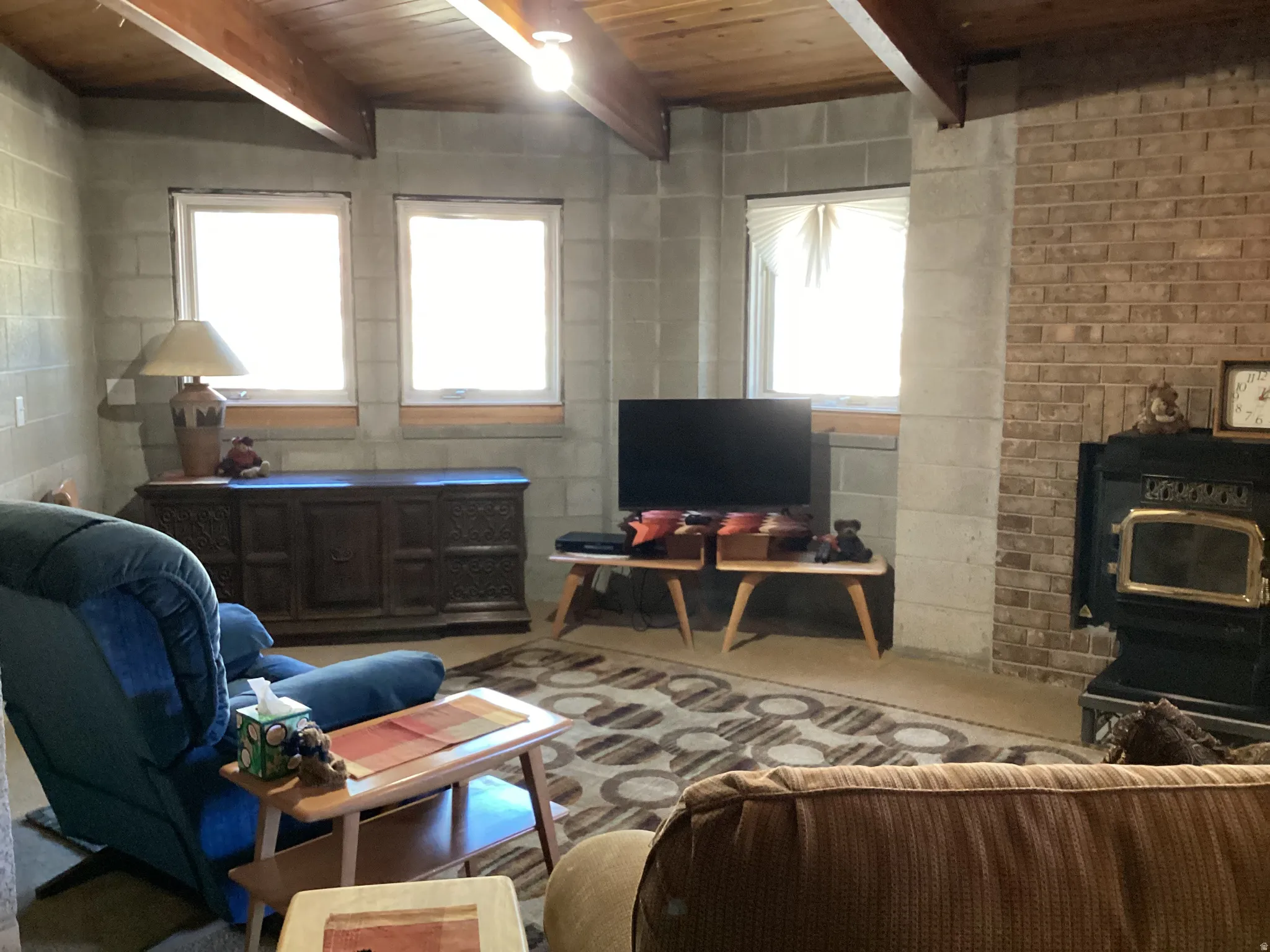 Living area featuring a wood stove and a wooden ceiling with exposed beams
