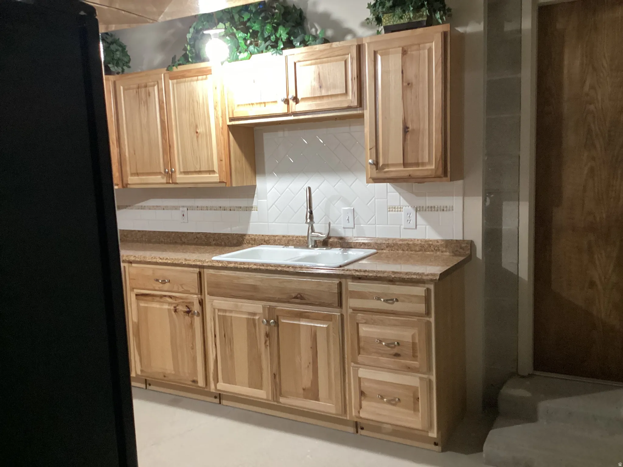 Kitchen featuring freestanding refrigerator, light wood finish cabinets, and tasteful backsplash