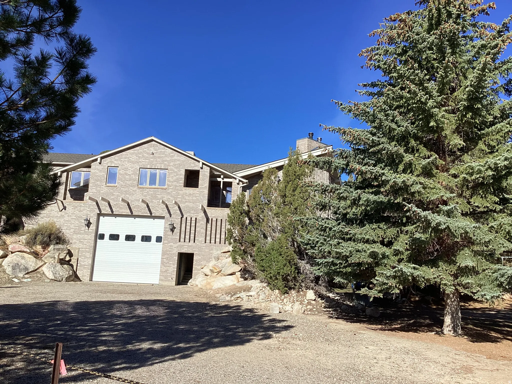 View of front of house with an attached garage, a chimney, driveway, and a balcony