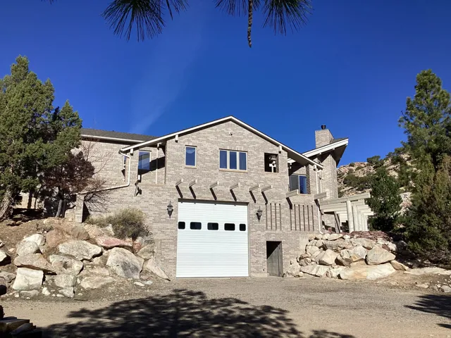 View of front of home with a garage, brick siding, a chimney, and driveway