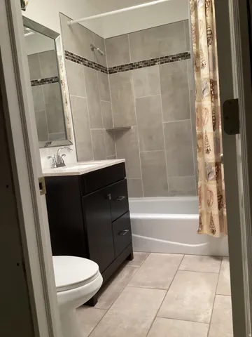 Bathroom with vanity, shower / tub combo with curtain, and light tile patterned flooring