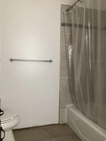 Full bath with light tile patterned flooring and shower / bath combo