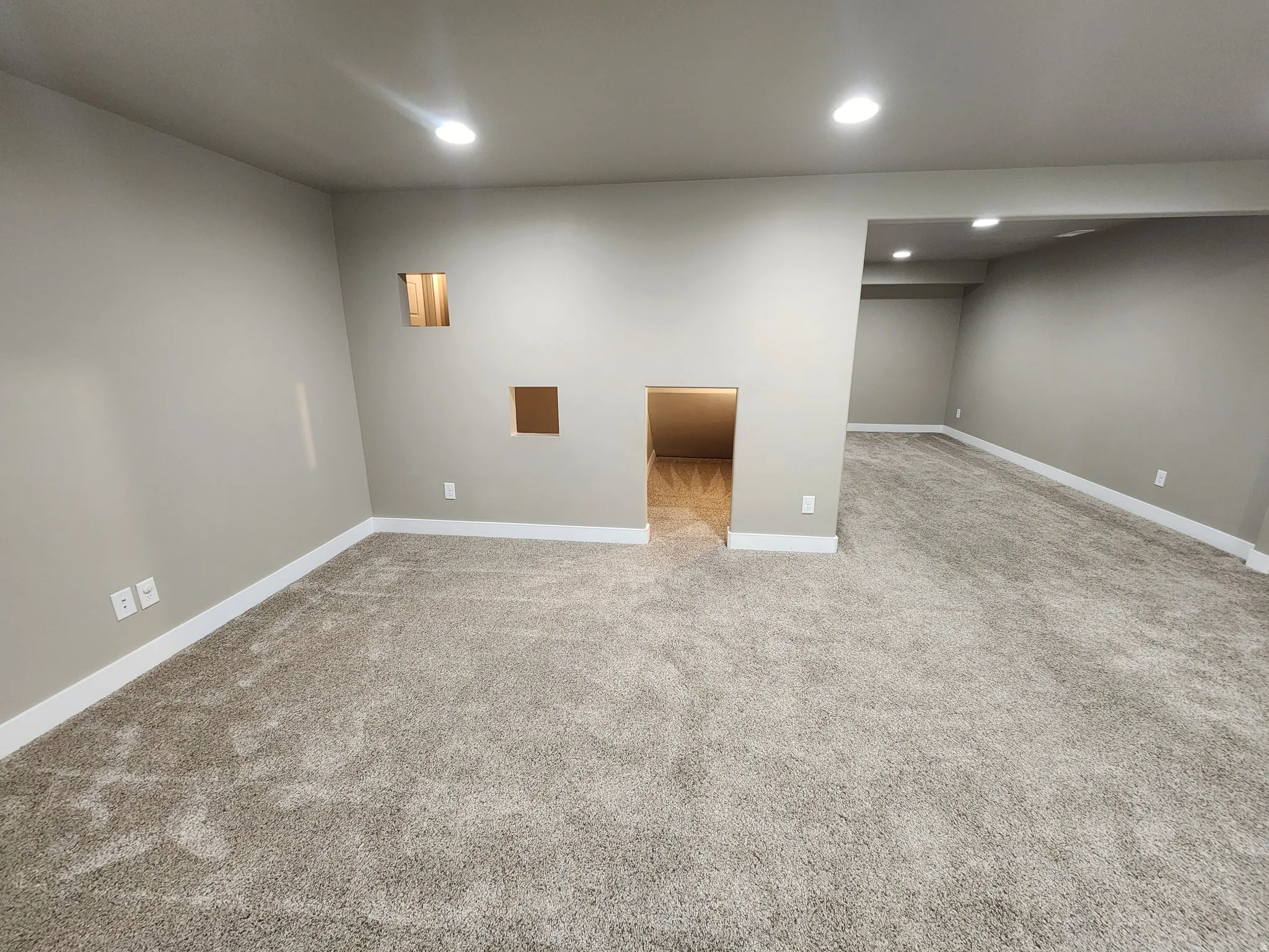 Finished basement with light colored carpet and recessed lighting