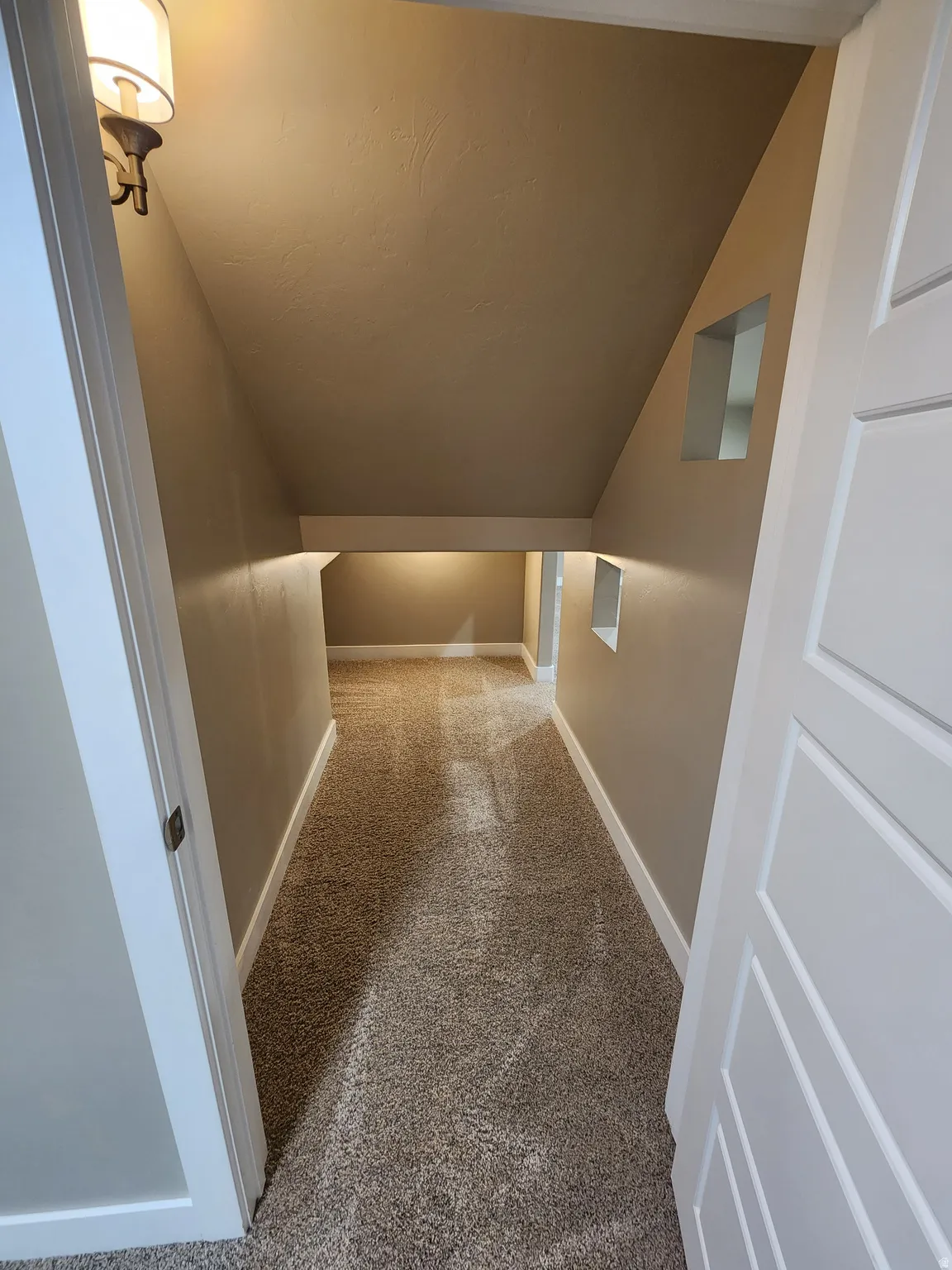 Corridor featuring lofted ceiling and light carpet