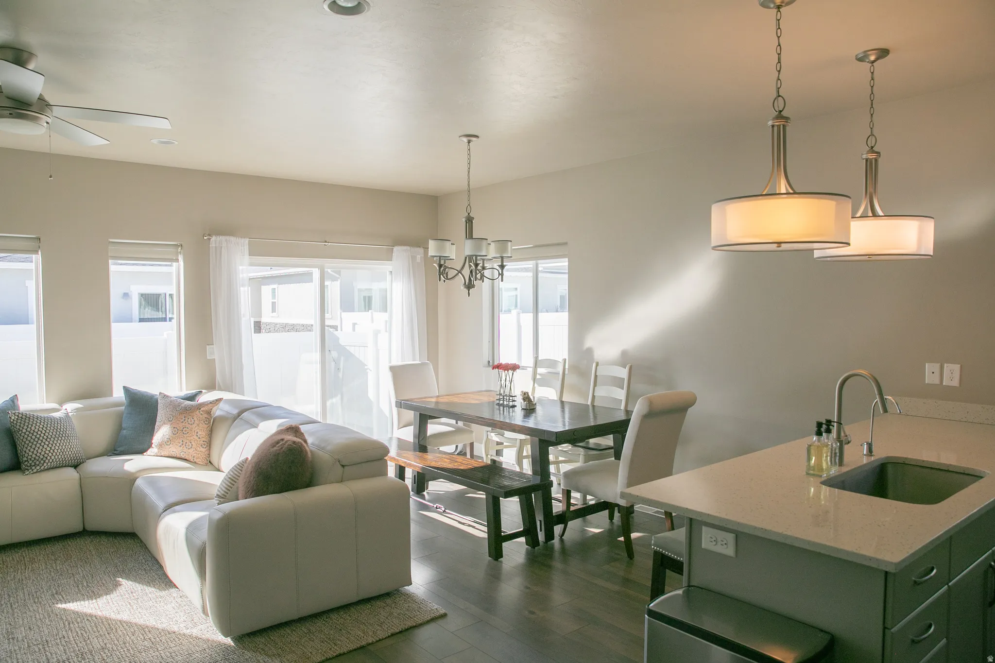 Living area featuring dark wood-style floors, ceiling fan, and a chandelier