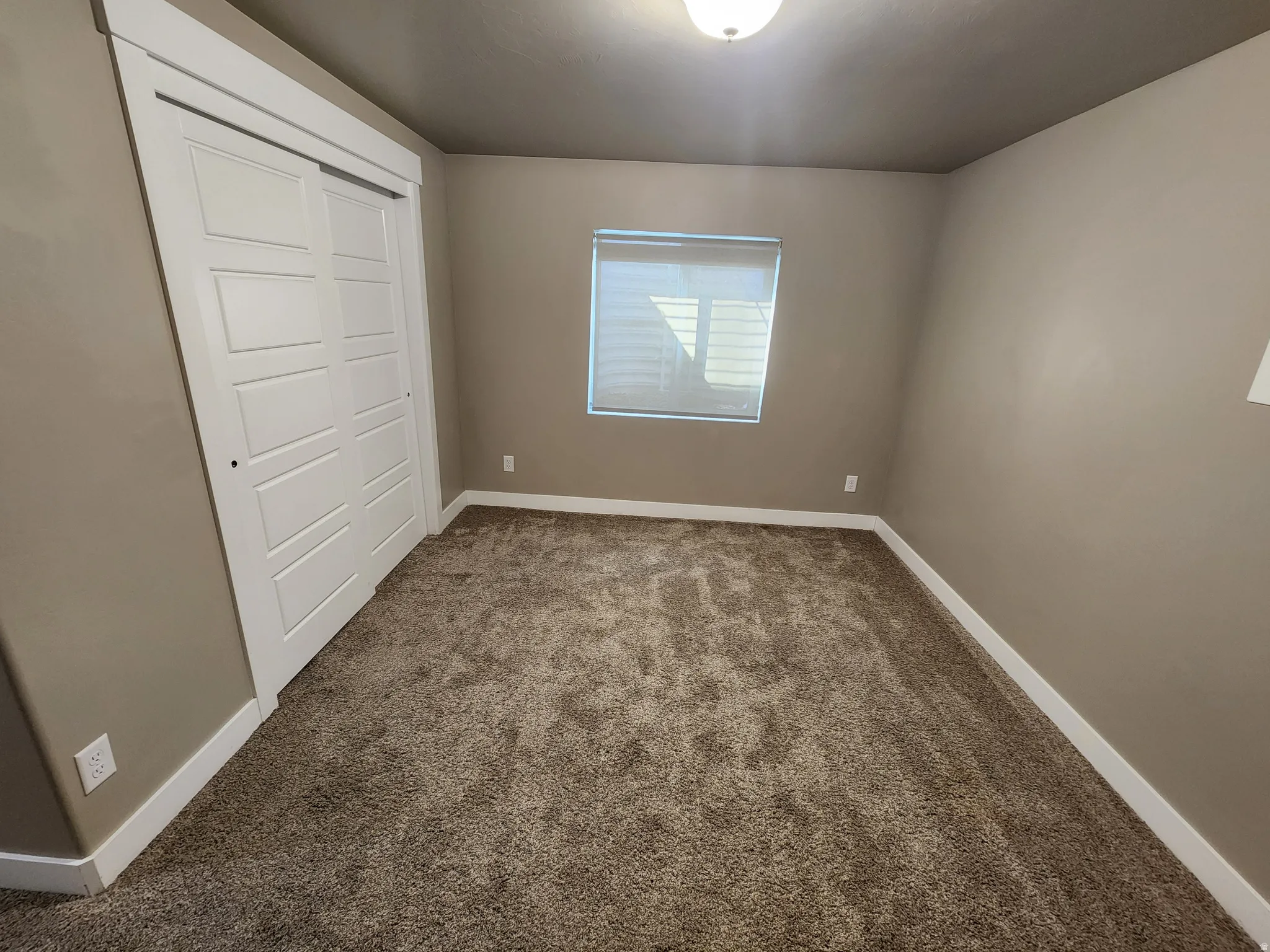 Unfurnished bedroom featuring a closet and dark carpet