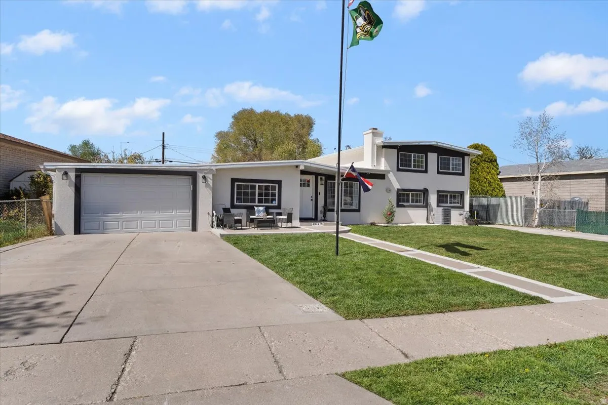 View of front facade featuring an attached garage, stucco siding, driveway, and a chimney