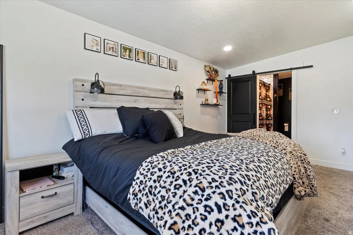 Bedroom with a barn door and light colored carpet