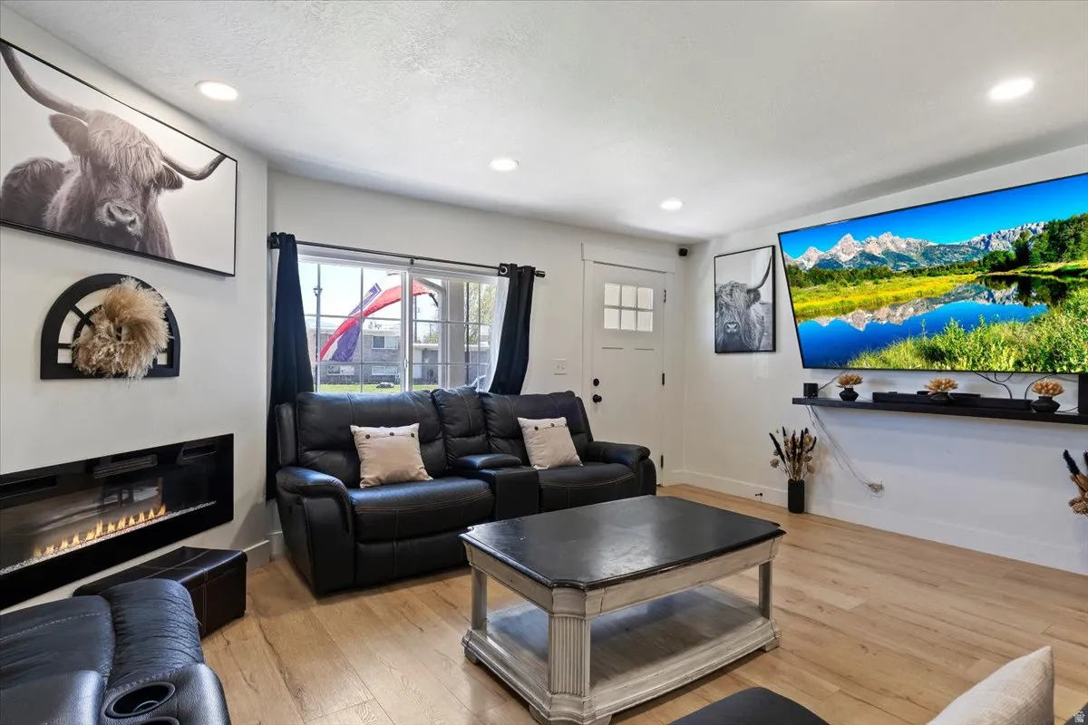 Living area with light wood-style floors, a glass covered fireplace, and recessed lighting