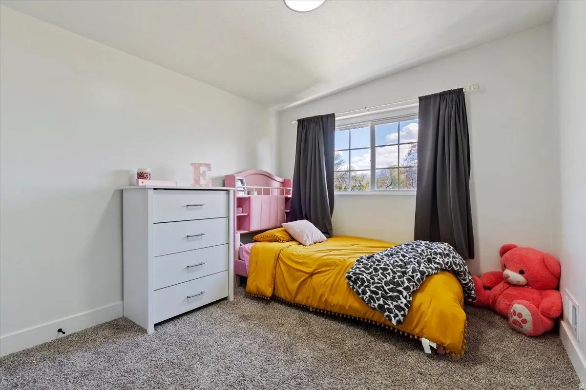 Carpeted bedroom featuring baseboards and vaulted ceiling