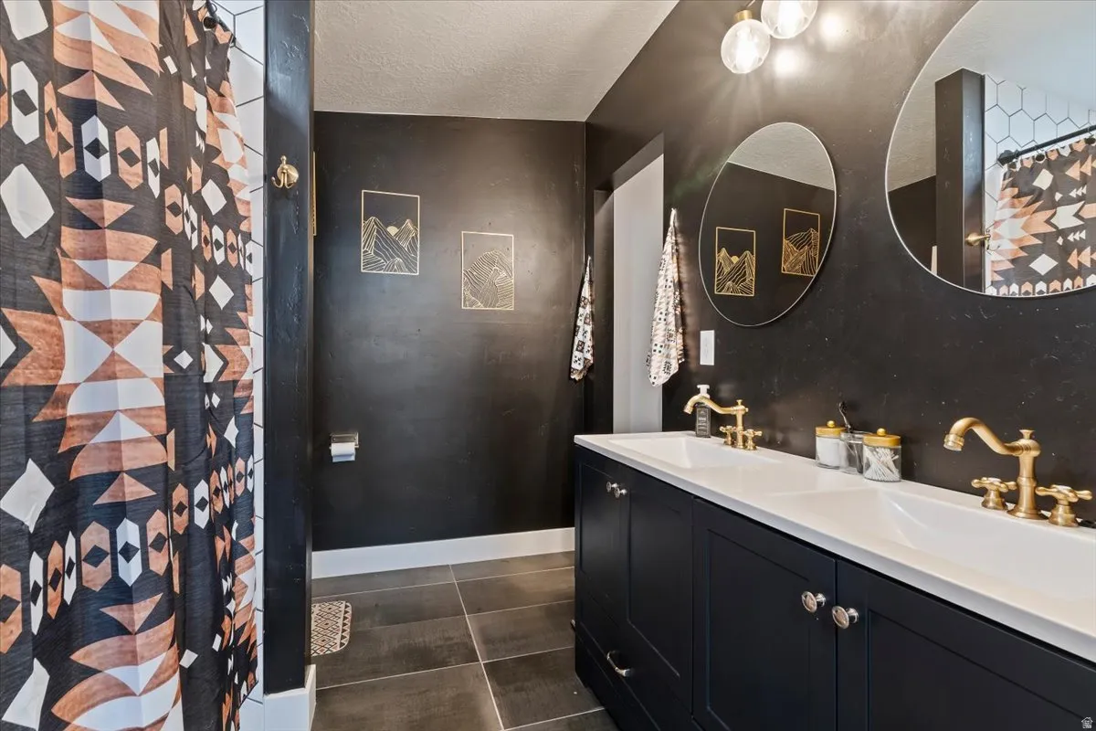 Bathroom with double vanity, a textured ceiling, and a shower with shower curtain