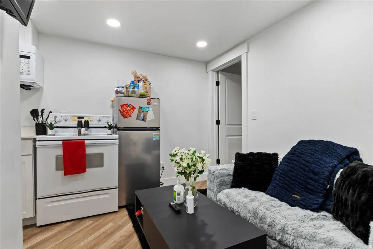 Kitchen with white electric stove, freestanding refrigerator, light wood-style flooring, recessed lighting, and light countertops