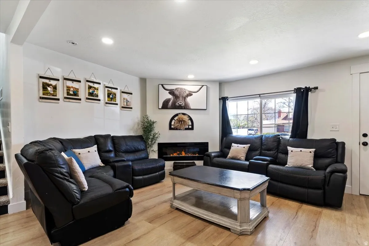 Living room featuring light wood-type flooring, recessed lighting, and a glass covered fireplace