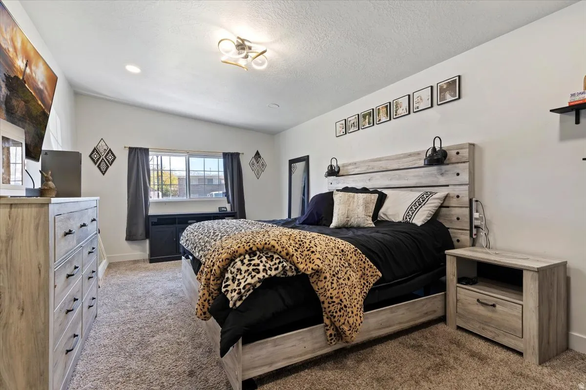 Bedroom featuring light colored carpet and a textured ceiling