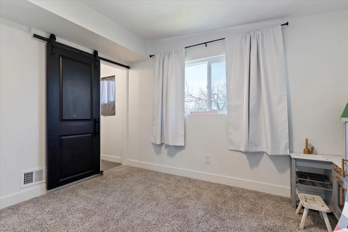 Carpeted bedroom with a barn door and baseboards