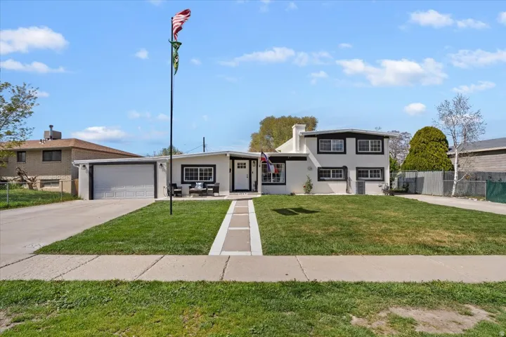 View of front of property with driveway, an attached garage, stucco siding, and a chimney