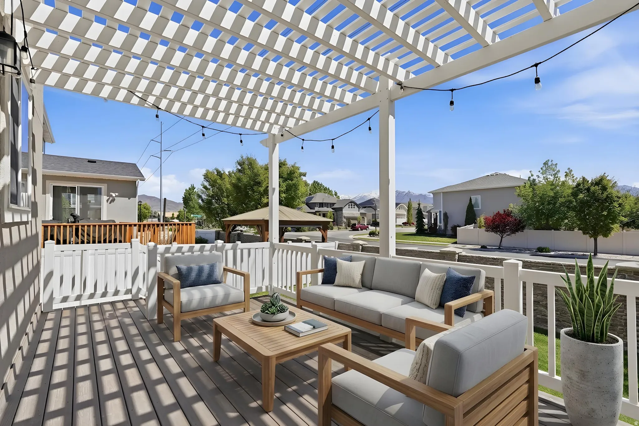 Expansive outdoor deck featuring a white slatted pergola and string lighting
