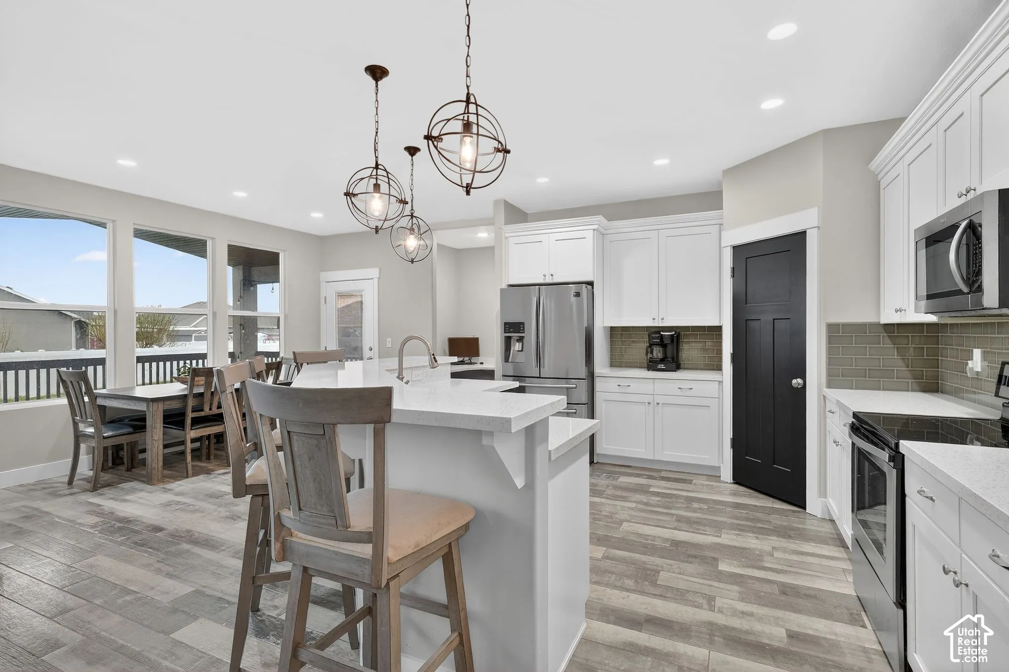 Kitchen with stainless steel appliances, a kitchen breakfast bar, white cabinetry, decorative backsplash, and an island with sink