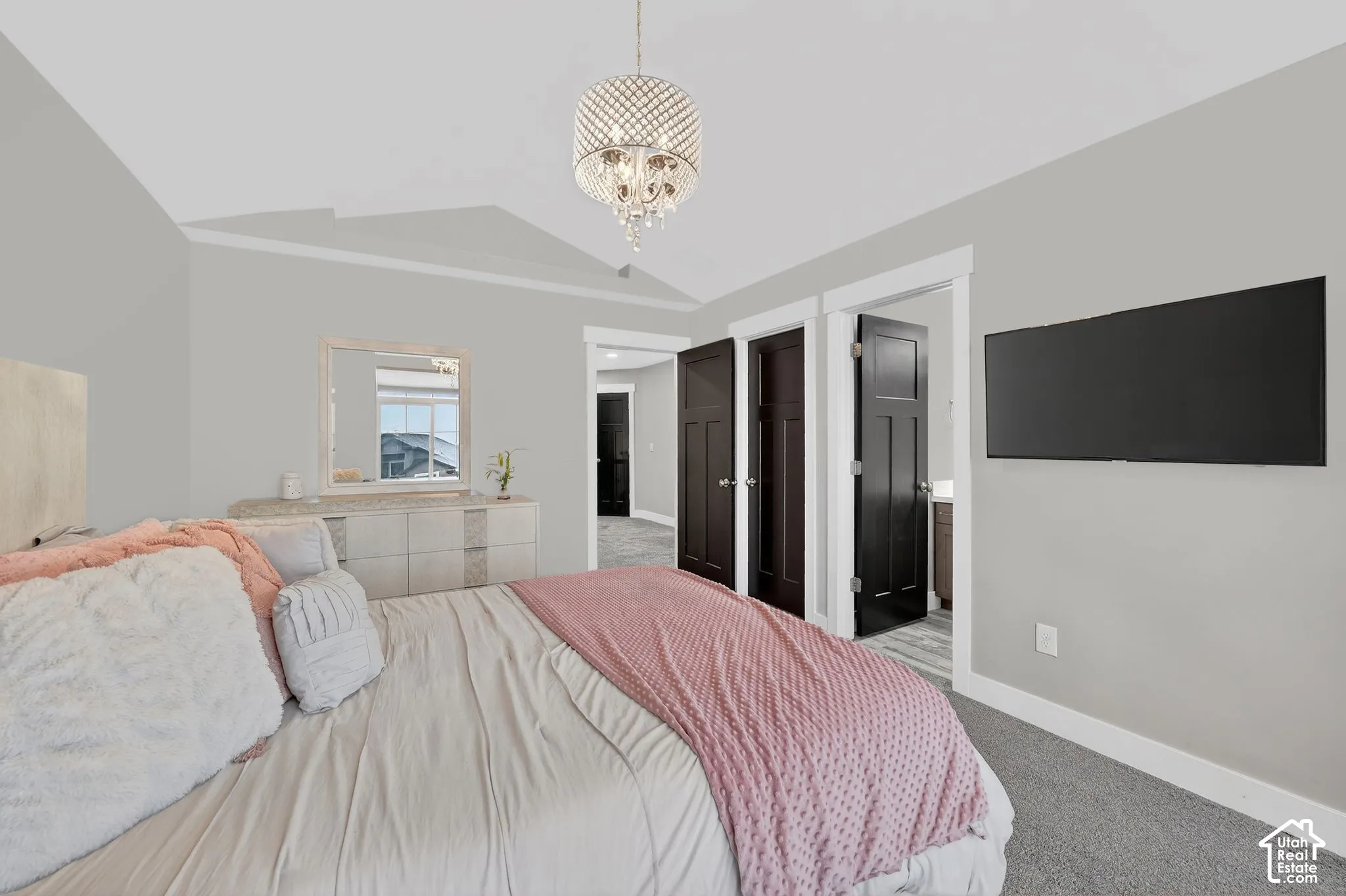 Bedroom featuring light carpet, suspended lighting, and ensuite bath