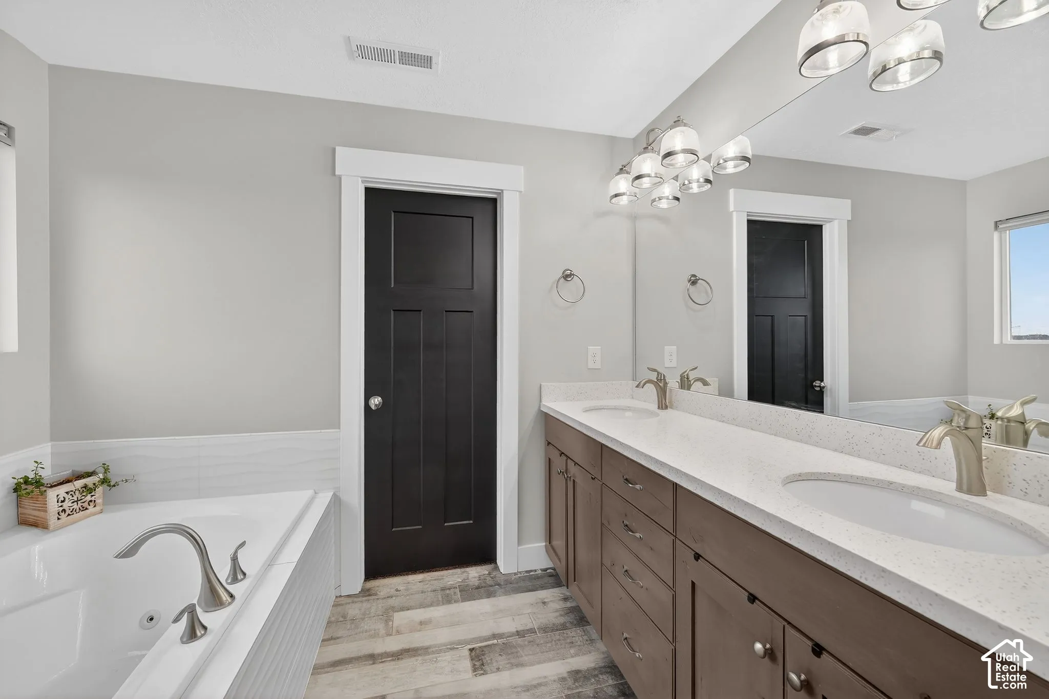 Bathroom featuring a jetted tub, double vanity, and light wood-style floors