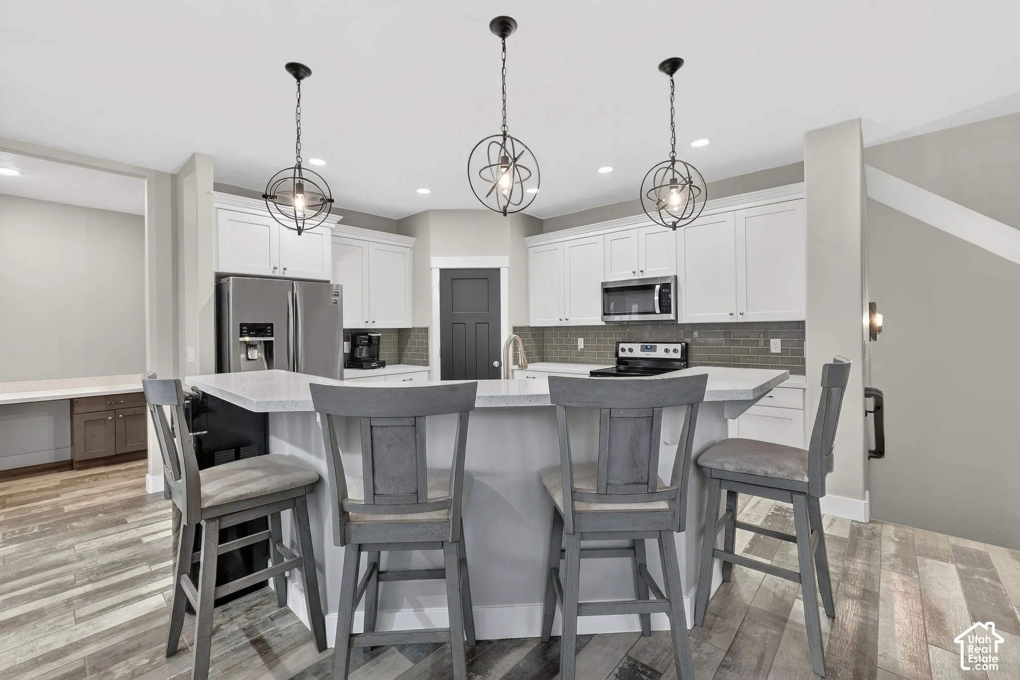 Dual tone kitchen with stainless steel appliances, a kitchen breakfast bar, dual tone cabinetry, backsplash, and a large island
