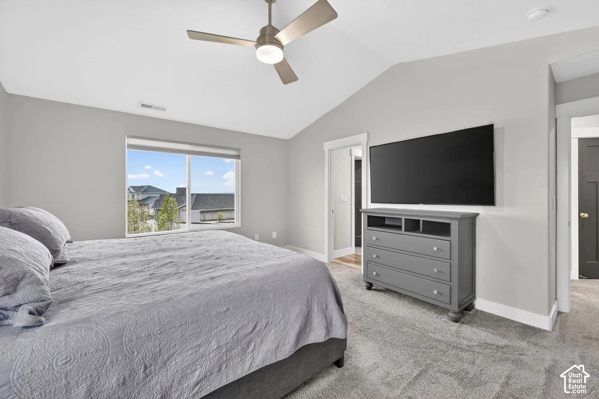 Bedroom featuring vaulted ceiling, light carpet, and a ceiling fan