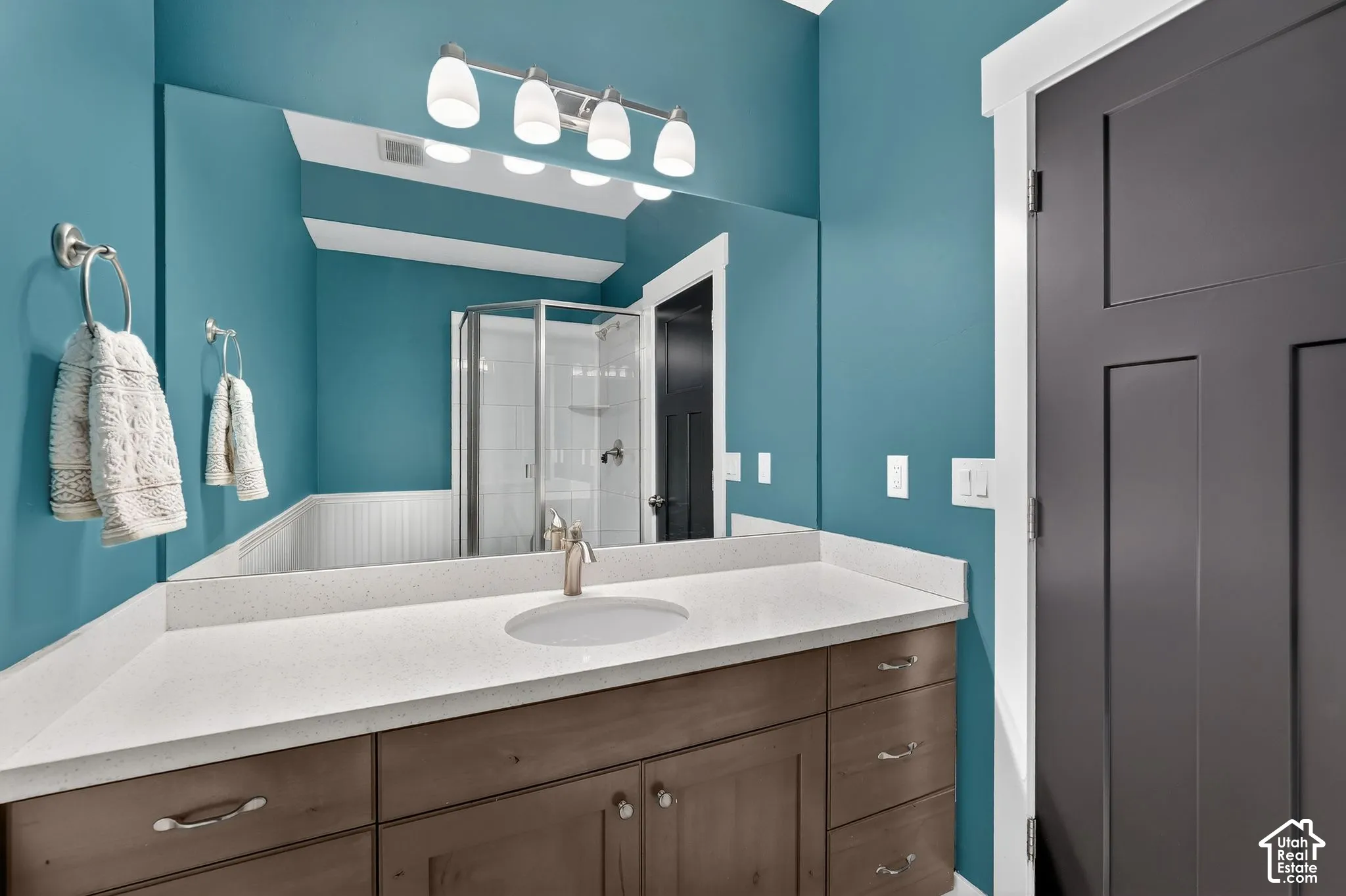 Full bath with a shower stall, vanity, and a wainscoted wall
