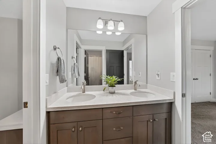 Bathroom with double vanity, a shower with shower curtain, and carpet flooring